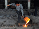 A Chinese worker pours molten steel into A Chinese worker pours molten steel into